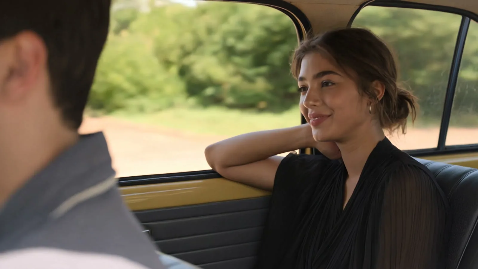 A woman riding in the back seat of a sunlit car