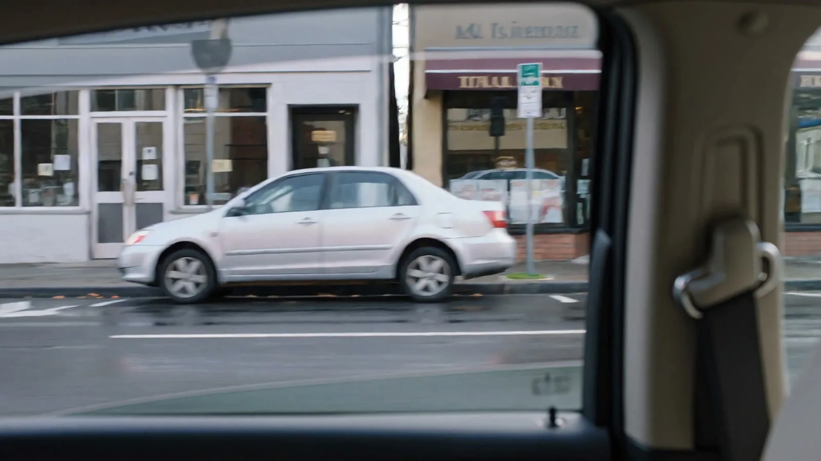 A city street seen through the window of a moving car